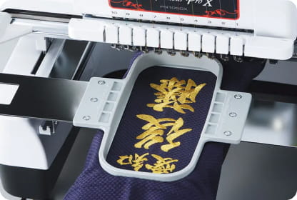 Embroidered golden letters in embroidery frame