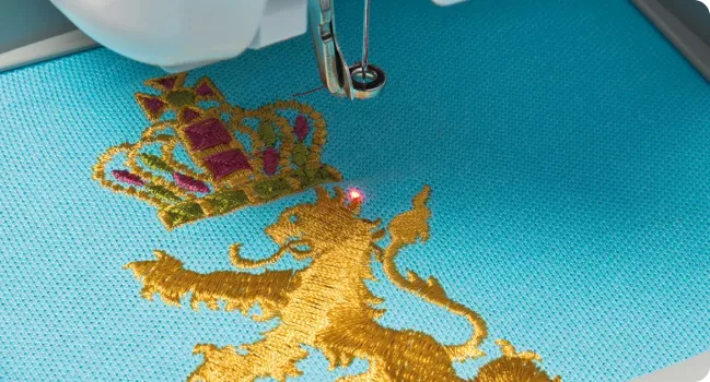 Red LED pointer on golden embroidered lion on blue fabric
